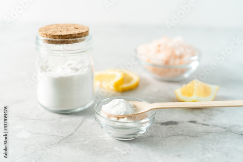 Eco friendly natural cleaners, jar with baking soda, lemon, pink salt and wooden spoon on marble table background. Organic ingredients for homemade cleaning. Zero waste concept.