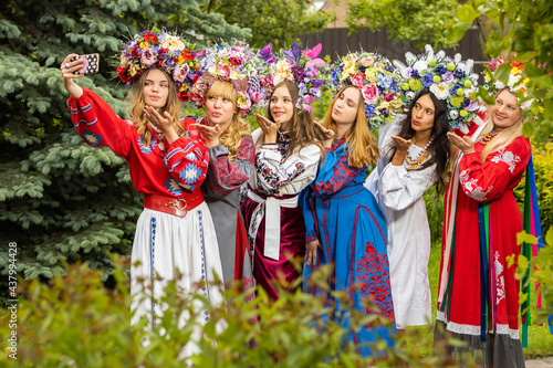 Girls in national Ukrainian costumes are photographed against the backdrop of a green garden photo