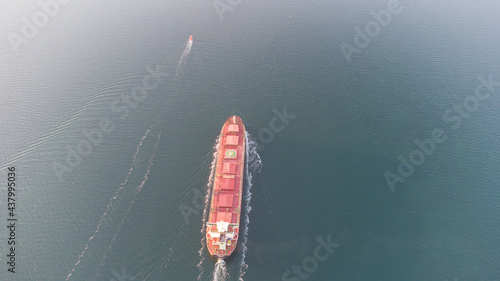A large ocean-going cargo ship moves out to sea on calm waters. Dry cargo ship aerial view. © Виктор Кеталь