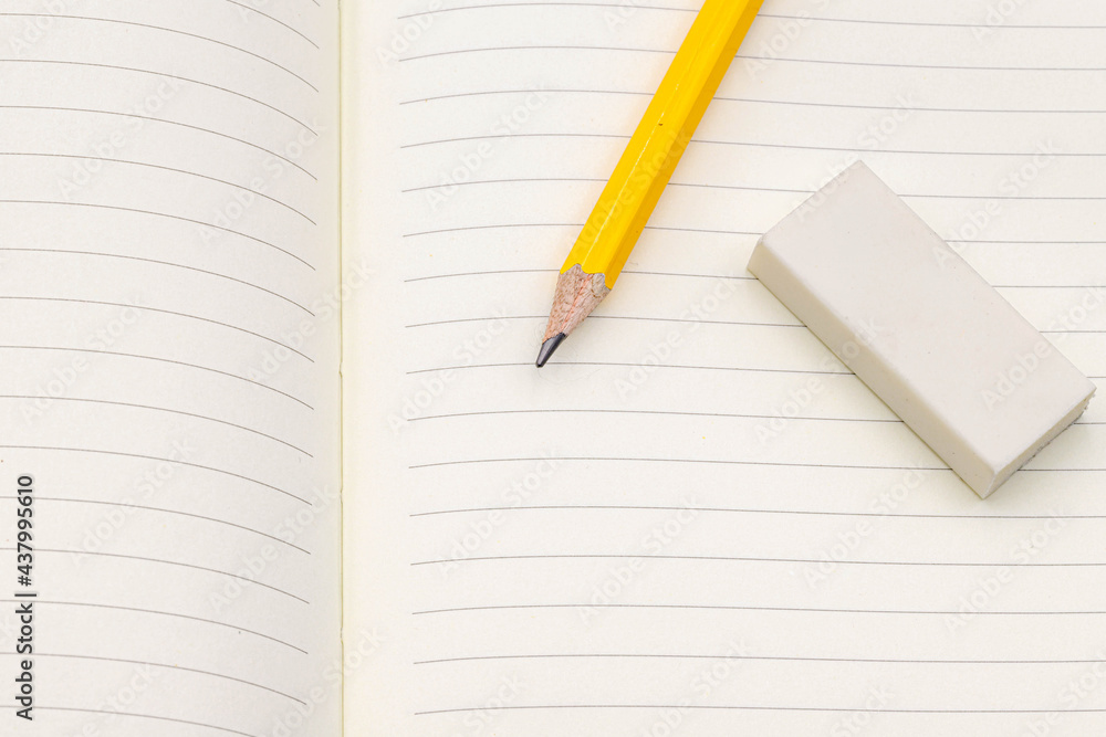 Writing concept, Half opened book with yellow pencil and eraser on, Detail of white paper and line in blank notebook. Writing concept, Half opened book with yellow pencil and eraser on, Detail of white paper and line in blank notebook.