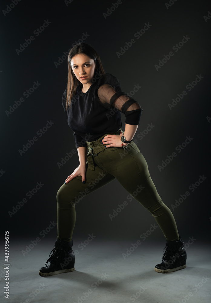 Fototapeta premium Portrait of beautiful model in black dress, hat and sunglasses on gray background