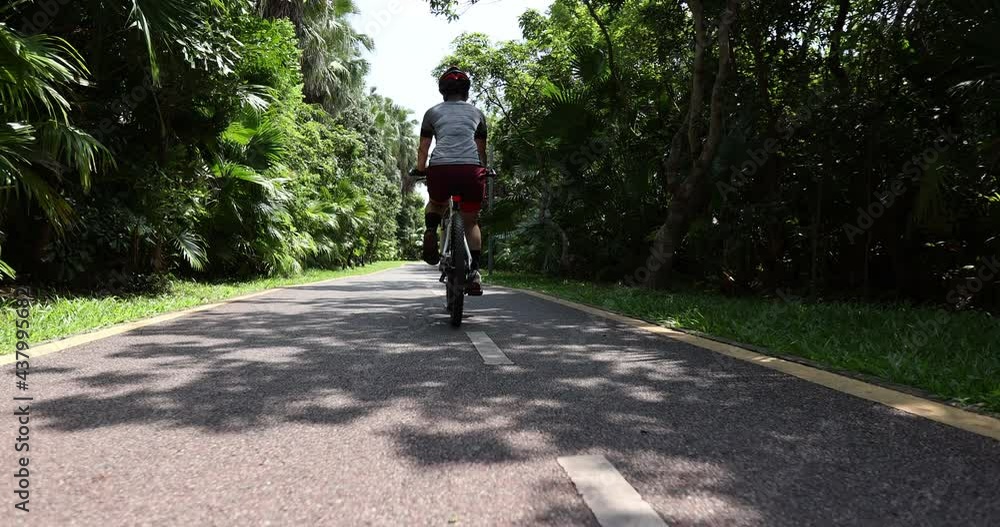 Woman riding a bike on tropical park trail in summer Woman riding a bike on tropical park trail in summer