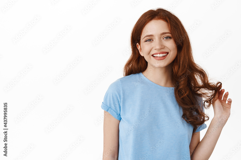 Beautiful modern redhead girl playing with curly ginger hair, smiling white teeth, looking happy and relaxed. Natural face of young woman and cheerful emotion, white background Beautiful modern redhead girl playing with curly ginger hair, smiling white teeth, looking happy and relaxed. Natural face of young woman and cheerful emotion, white background