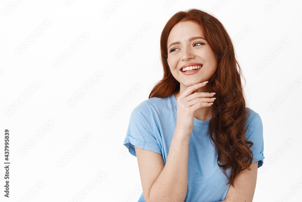 Candid ginger girl laughing, smiling white teeth, looking aside at left copyspace with happy, relaxed natural expression, standing against white background Candid ginger girl laughing, smiling white teeth, looking aside at left copyspace with happy, relaxed natural expression, standing against white background