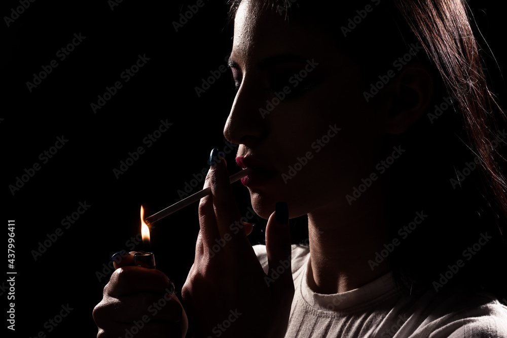 Obraz premium Silhouette of a woman lighting up a cigarette