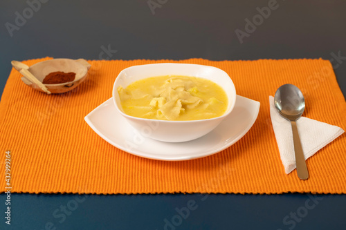 traditional soup of ecuadorian cuisine, bow noodle soup served in white plates and orange background