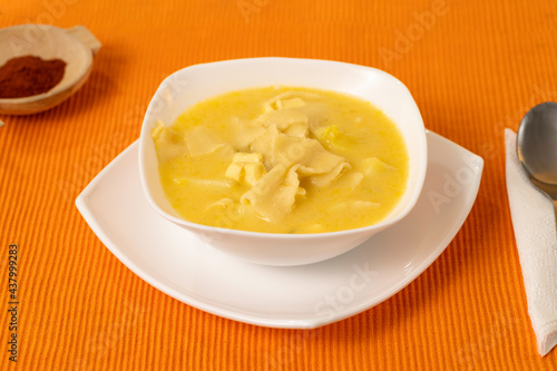 traditional soup of ecuadorian cuisine, bow noodle soup served in white plates and orange background