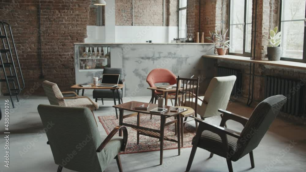 No people aerial shot of stylish loft workspace for business people and freelancers with designer chairs and wooden tables with gadgets and stationery on them No people aerial shot of stylish loft workspace for business people and freelancers with designer chairs and wooden tables with gadgets and stationery on them