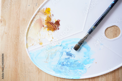 Acrylic sea and beach painting on drawing stand with palette and brush. Blue wave on golden sand hand painting with brush and knife palette technique. Art on canvas.