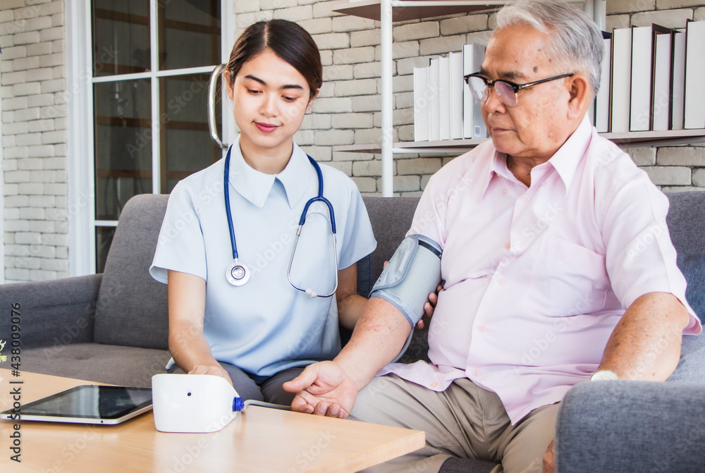 Fototapeta premium senior man at the nursing home concept. Nurse measures the elderly's blood pressure and pulse at the sitting room at the care center nursing home looking together