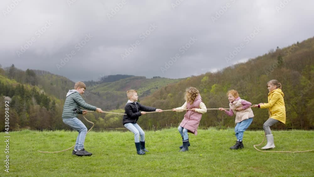 Group of school children doing rope pulling outside in nature. Group of school children doing rope pulling outside in nature.