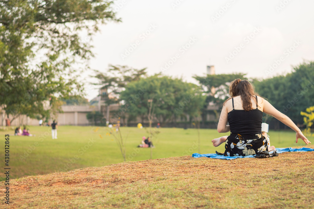 Obraz premium Young girl seated and reading a book in a park