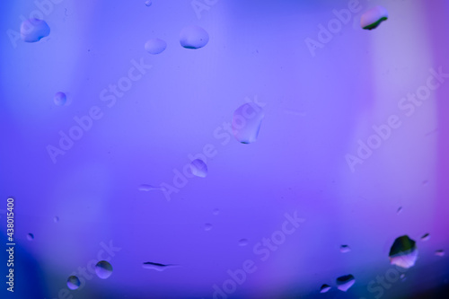 Close up water drops on glass with purple violet lighting