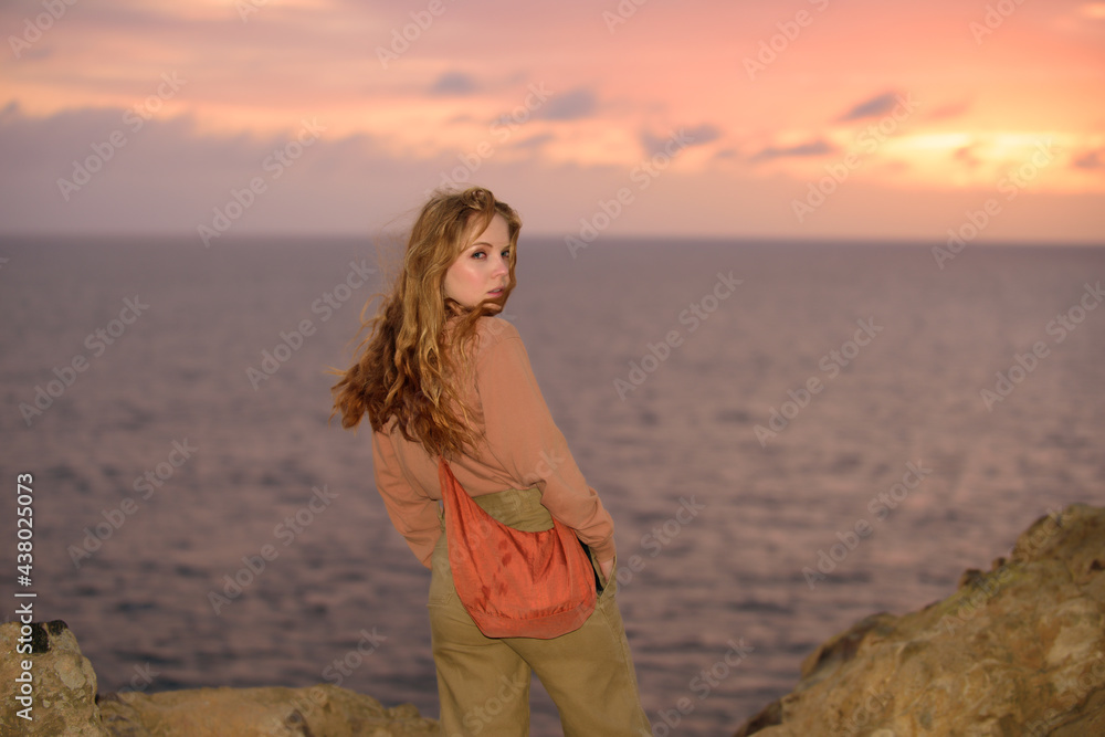 Obraz premium Woman in autumn fashion dress on the ocean coast, on rocky beach.