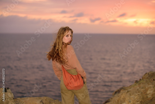 Woman in autumn fashion dress on the ocean coast, on rocky beach.