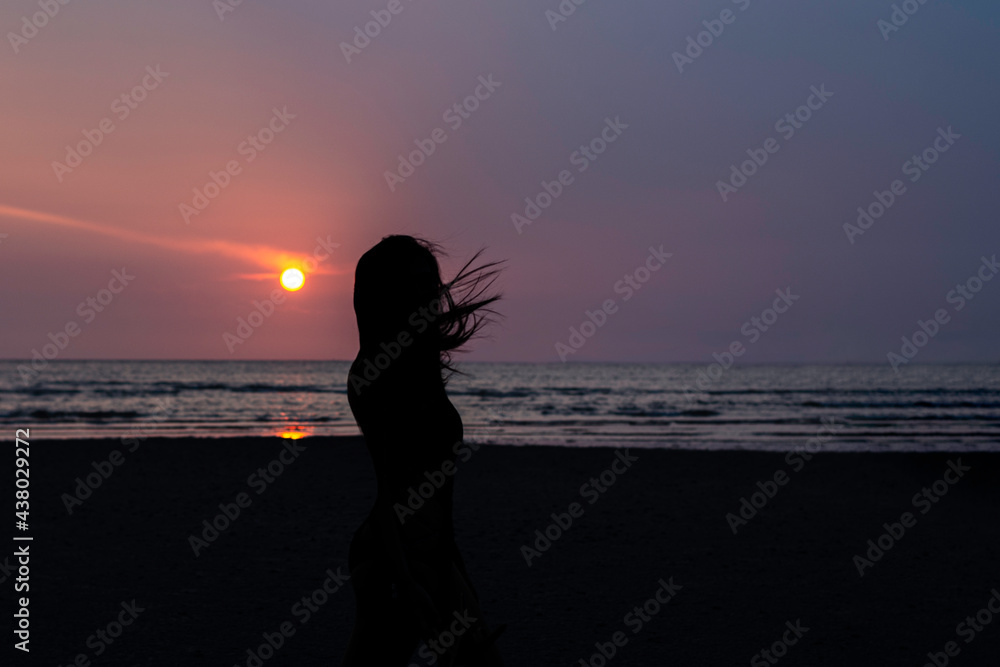 Women silhouette on beach during sunset.