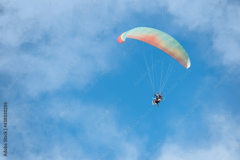 People flying free on a colorful paraglider through the clouds on a blue sky with copy space People flying free on a colorful paraglider through the clouds on a blue sky with copy space