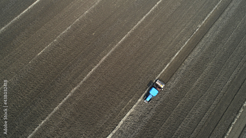 Fototapeta premium Farmers drive tractors to level up land, North China