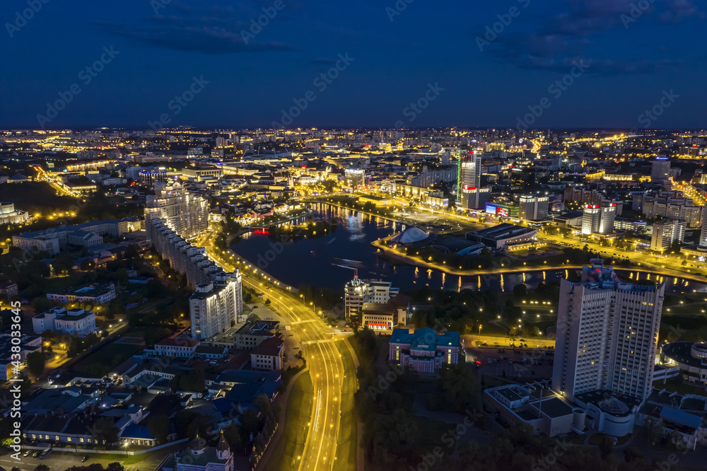 aerial cityscape view with illuminated buildings and streets in Minsk city at night.