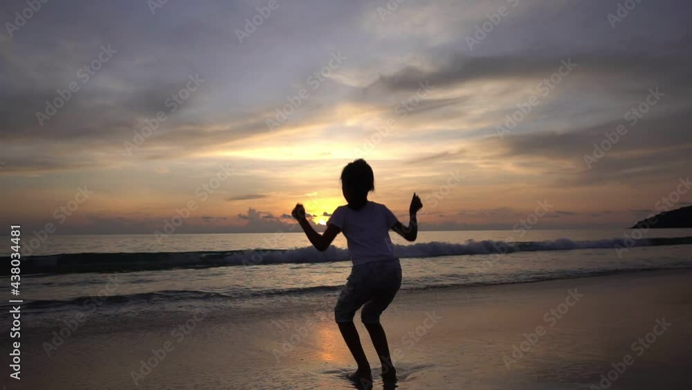Silhouette Asian teen girl 6 years old standing on beach at sunset raising arms on beach enjoying Amazing sunset or sunrise on summer travel vacation holiday Happiness travel and bliss concept video Silhouette Asian teen girl 6 years old standing on beach at sunset raising arms on beach enjoying Amazing sunset or sunrise on summer travel vacation holiday Happiness travel and bliss concept video