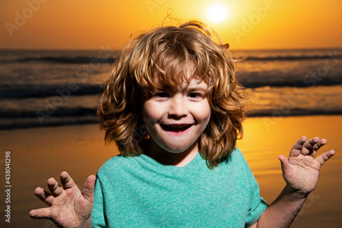 Kid boy portrait on sunset beach, thumbs up. Amazed surprised kids emotions with fynny face. photo