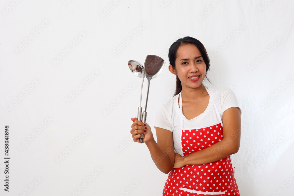 Portrait of asian woman wearing kitchen apron while holding a cooking utensil. Isolated on white background Portrait of asian woman wearing kitchen apron while holding a cooking utensil. Isolated on white background