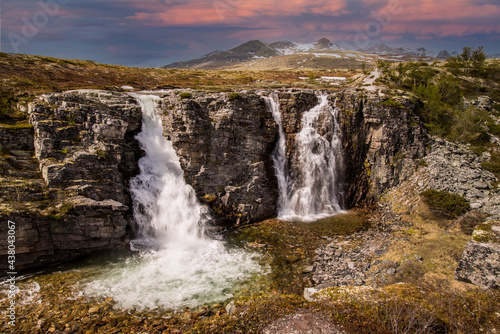 beautiful waterfalls with crystal clear water with mountains in the background at sunset Norway.