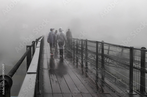 Pessoas caminhando na ponte de Paranapiacaba. Dia nublado, frio com névoa e neblina e chuva. photo