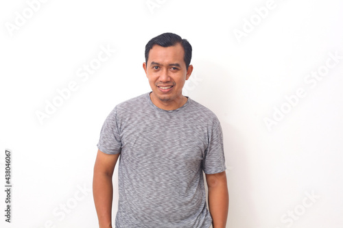 Smile happy face of ordinary Asian man in grey shirt. Concept of charming and positive thinking. Isolated on white background