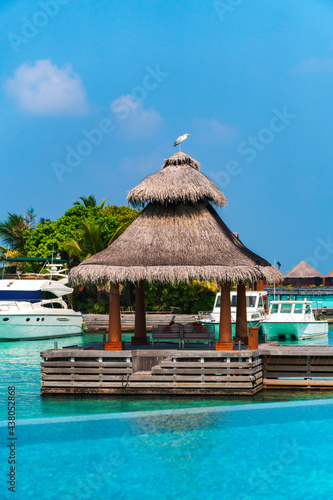 Scenic landscape of Maldives beach and pier with speed boats and yachts on the horizon. Seascape with water bungalows, beautiful turquoise sea and lagoon waters, tropical nature paradise. 