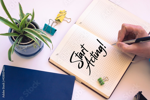 Closeup of a personal agenda setting an important date writing with pen. The words Start Acting written on a white notebook to remind you an important appointment.