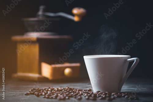 coffee beans  with coffee grinder and hot cup of coffee on  table in coffee shop, copy space for text.