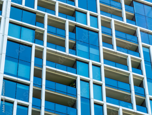 Modern windows and balconies close up in a multi-dwelling building. Apartments in a strata living scheme of common property.