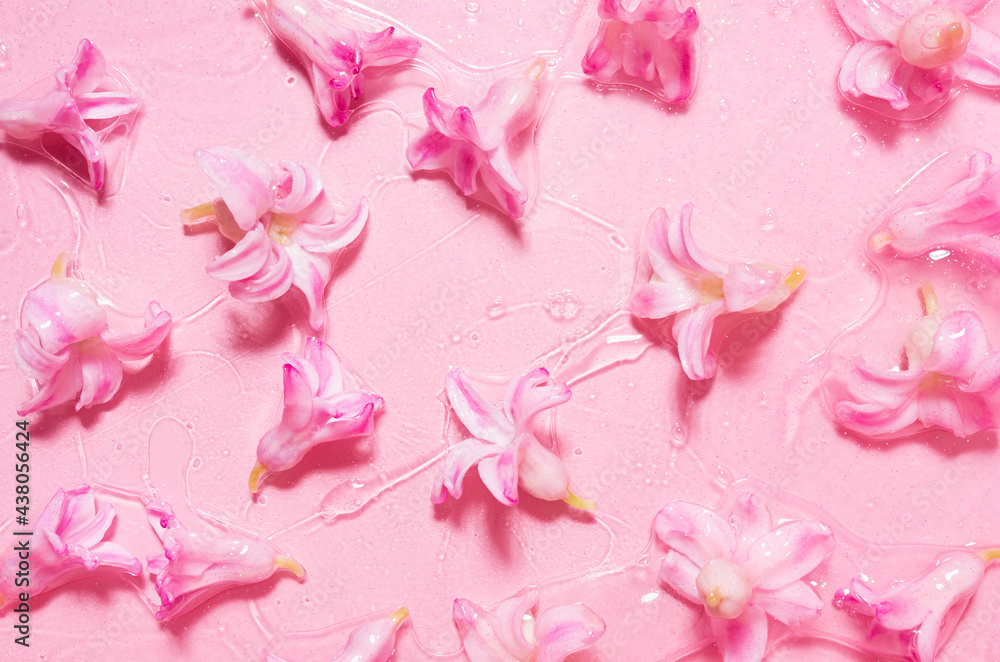 Spring pink wet hyacinth flowers with gold glitter glowing under cosmetic transparent gel on pink background, top view, pattern. Spring pink wet hyacinth flowers with gold glitter glowing under cosmetic transparent gel on pink background, top view, pattern.