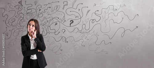 Thoughtful businesswoman with abstract arrows sketch on concrete wall background. Confusion and direction concept.