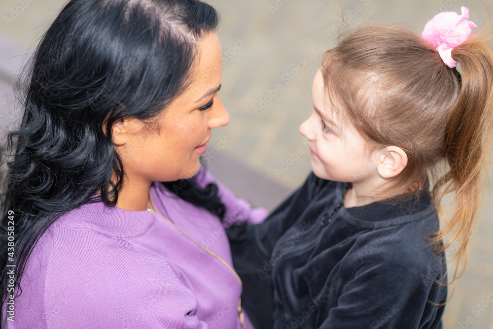 Cute 5 years old girl and her mom sit on a park bench in summer.Family and lifestyle concept.Closeup. Cute 5 years old girl and her mom sit on a park bench in summer.Family and lifestyle concept.Closeup.