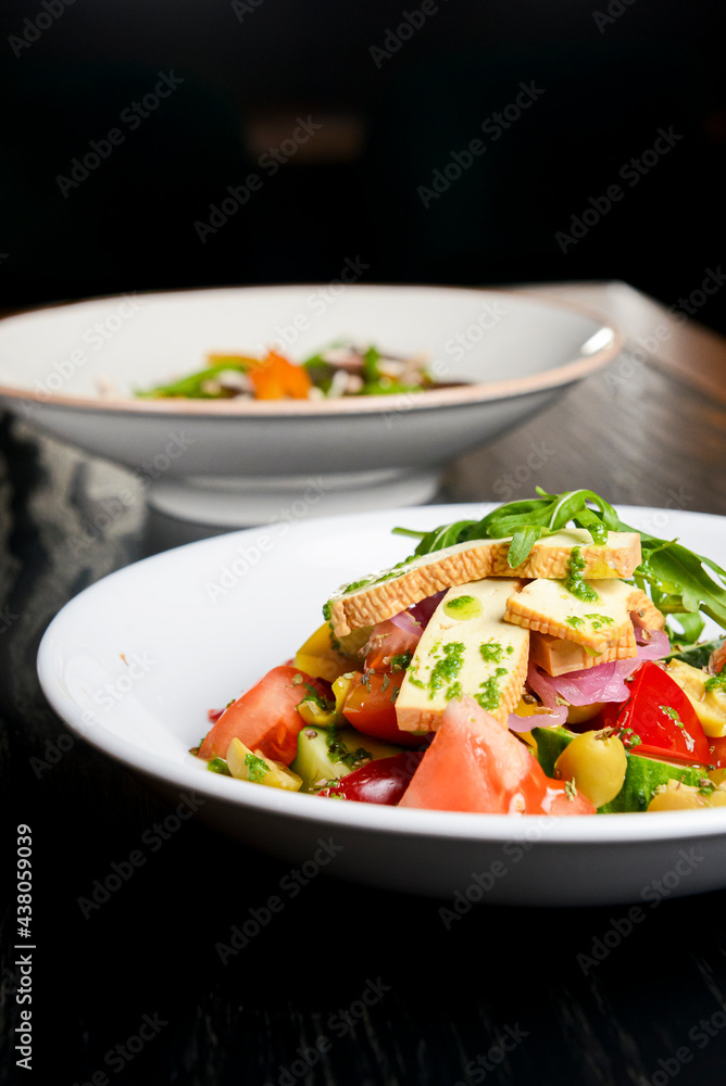 Buckwheat dumplings with fresh mushrooms and vegetable salad with cheese, fresh romatoes and cucumbers over black Buckwheat dumplings with fresh mushrooms and vegetable salad with cheese, fresh romatoes and cucumbers over black