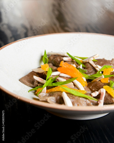 Buckwheat dumplings with fresh mushrooms served on a white plate over black background. photo