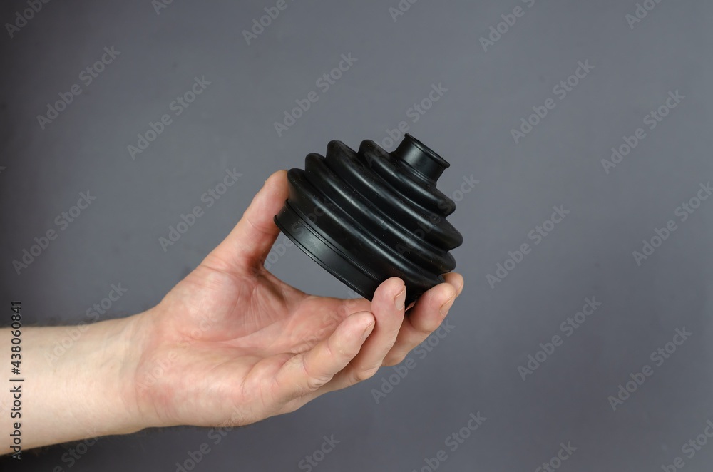 A man is hold Black rubber drive shaft cover against a gray back A man is hold Black rubber drive shaft cover against a gray back