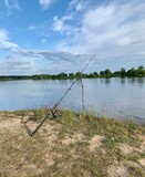 Fishing rod, spinning reel on the river bank. Wildlife. Fishing article. Out-of-town vacation concept.