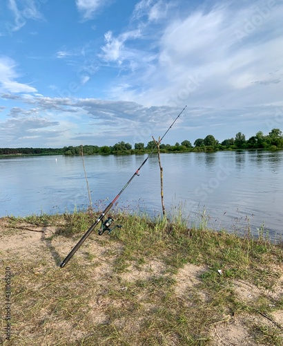 Fishing rod, spinning reel on the river bank. Wildlife. Fishing article. Out-of-town vacation concept.