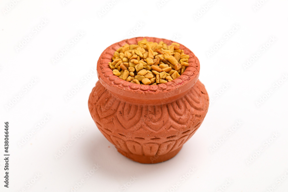 Dry seeds of fenugreek in a clay bowl isolated on white background. - obrazy, fototapety, plakaty 