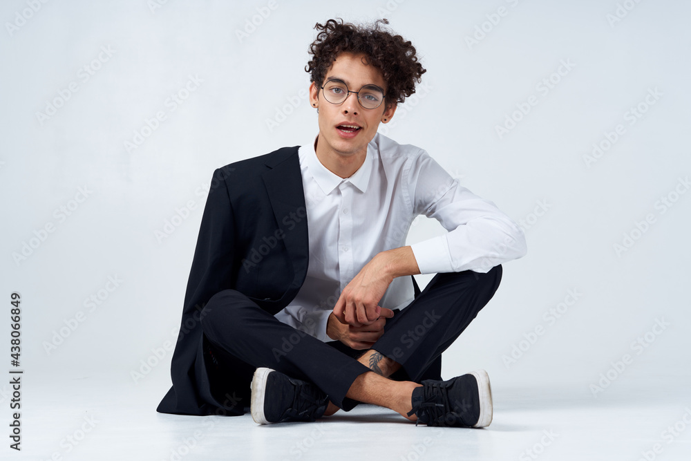 emotional guy in a classic suit sits on the floor in a bright room glasses on the face portrait model emotional guy in a classic suit sits on the floor in a bright room glasses on the face portrait model