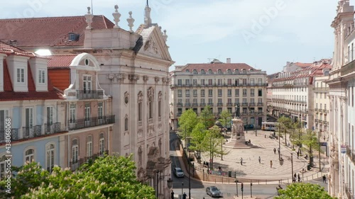 Traditional narrow city streets with beautiful architecture surrounding city square and pedestrians walking around city center in Lisbon, Portugal