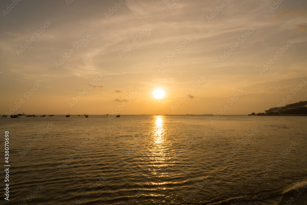 Obraz premium Beautiful sunset tropical beach with small boat and pink sky and ocean waves on a tropical sea at Vung Tau. Tropical Seascape with a boat on sandy beach at cloudy sunrise or sunset.