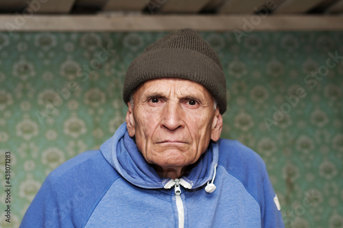 Portrait of old angry man with wrinkled face wearing knitted cap photo