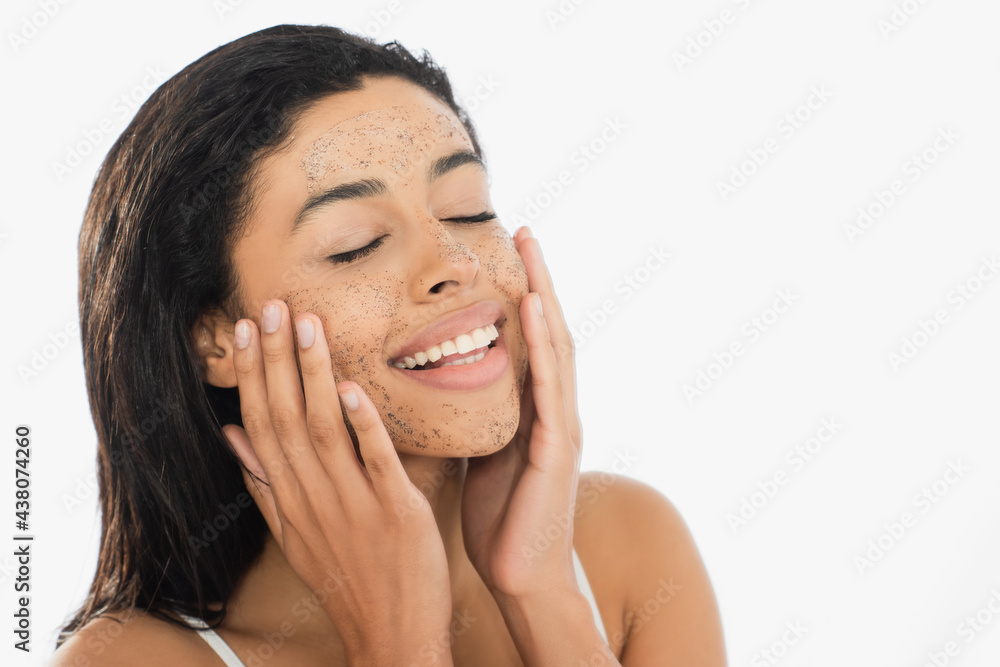 cheerful young african american woman with closed eyes touching face with scrub isolated on white cheerful young african american woman with closed eyes touching face with scrub isolated on white