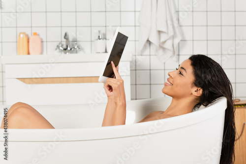 young african american woman taking bath and using digital tablet with blank screen