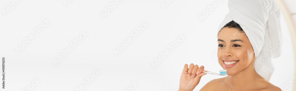 smiling young african american woman wrapped in towel holding toothbrush near face in bathroom, banner smiling young african american woman wrapped in towel holding toothbrush near face in bathroom, banner