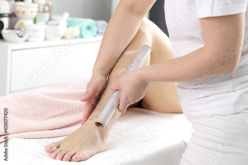The procedure is an anti-cellulite wrap in the salon by a massage specialist. The concept of professional body care with a copy of the space. Close-up